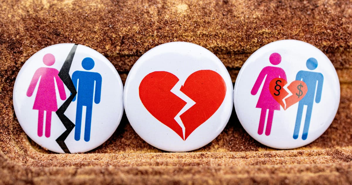 Three pin buttons on sand depicting divorce themes: split figures, a broken heart, and a couple holding a torn heart with legal and money symbols